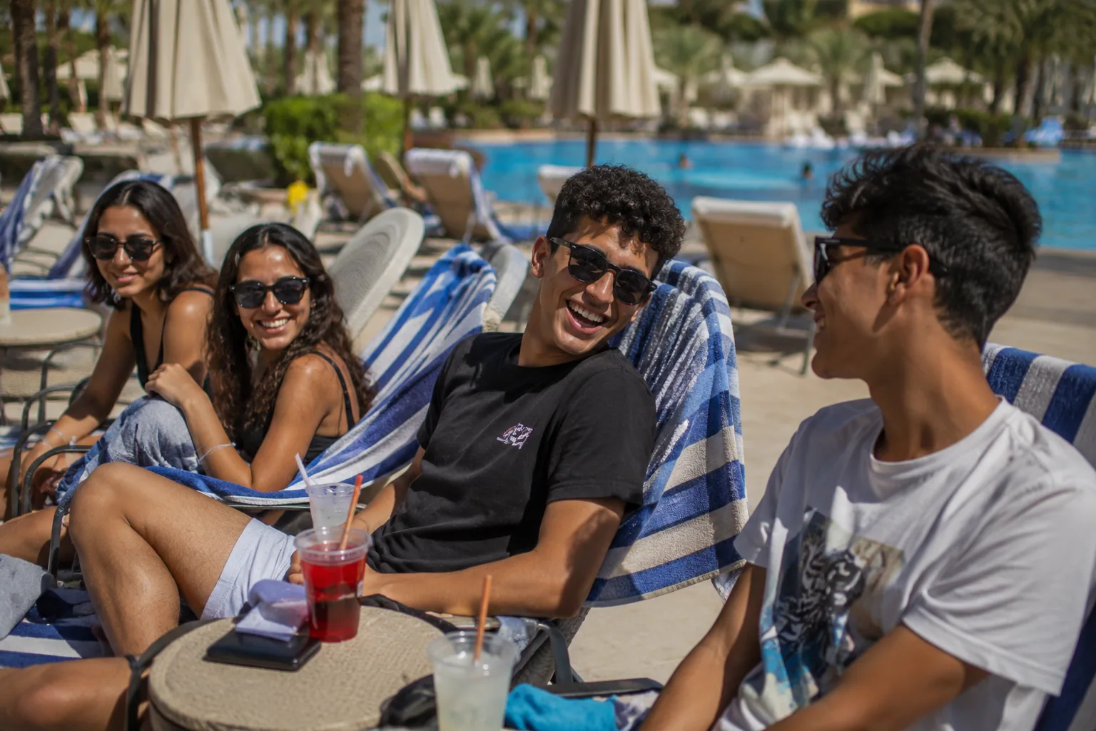 Students laughing together at a poolside lounge